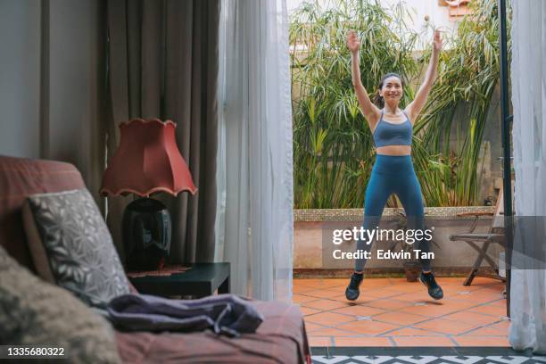 asian chinese beautiful woman jumping jack warming up exercise at front yard of her house - jumping jack stock pictures, royalty-free photos & images