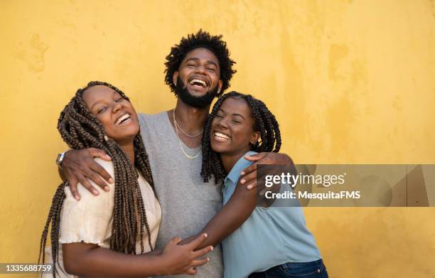 hugging afro people yellow background - adult siblings stock pictures, royalty-free photos & images