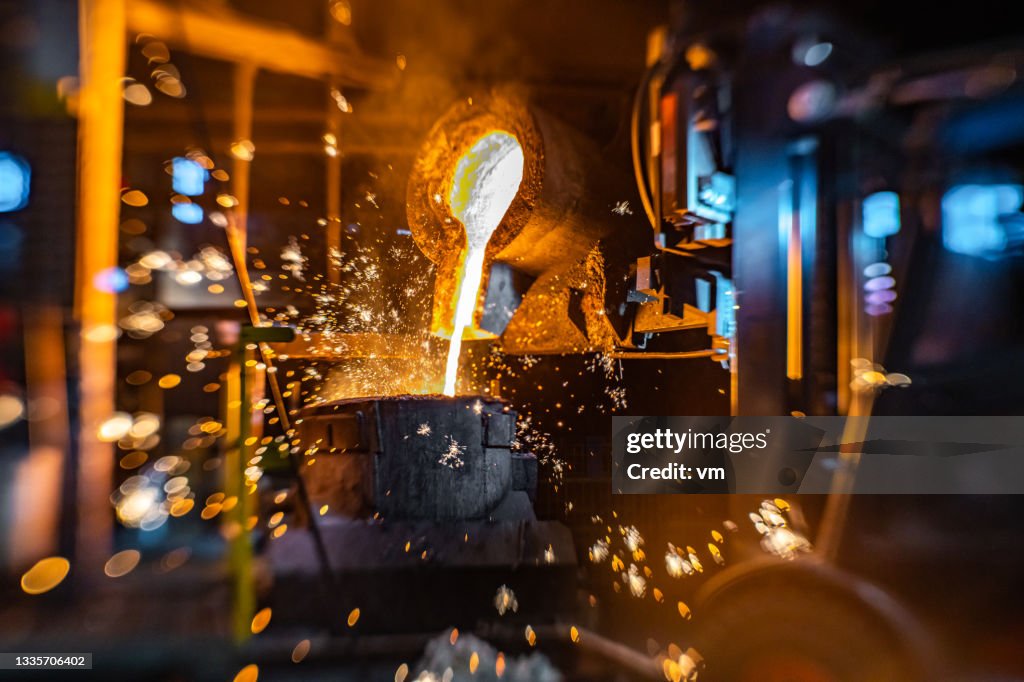 Close-up of work with liquid hot metal in foundry