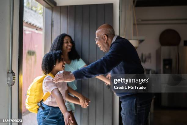 grandfather embracing granddaughters arriving at home - teenagers greeting stock pictures, royalty-free photos & images