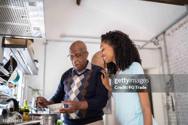 grandfather serving a soup bowl to granddaughter at home - teenager cooking stock pictures, royalty-free photos & images