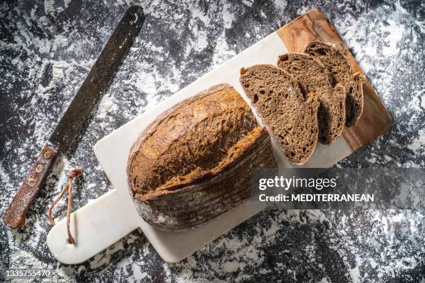 sourdough bread brown loaf wholegrain homemade german style on cutting board over flour - rye bread stock pictures, royalty-free photos & images