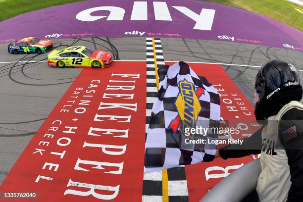 Ryan Blaney, driver of the Menards/Cardell Cabinetry Ford,takes the checkered flag to win the NASCAR Cup Series FireKeepers Casino 400 at Michigan...