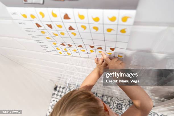 little girl putting stickers of pees and poops on calendar on the days where she has done each action. - childrens closet stockfoto's en -beelden