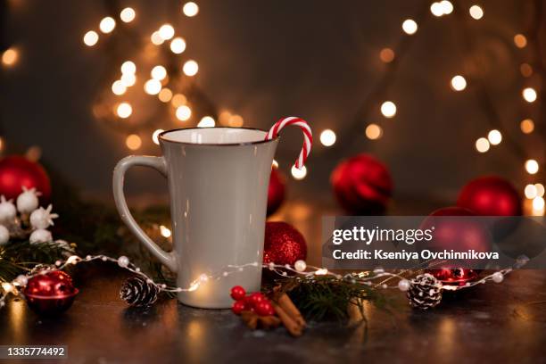 enamel cup of hot cocoa with marshmallows and candy canes in the shape of a heart against rustic background with beautiful christmas lights of bokeh. could also be coffee. blurred background. - coffee drink white background stock pictures, royalty-free photos & images