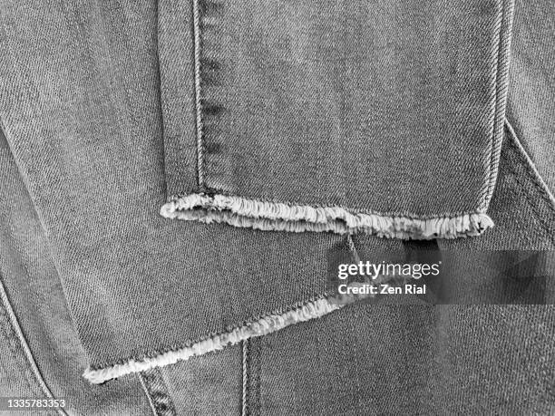 faded black denim jeans folded showing fringed hem - hem photos et images de collection