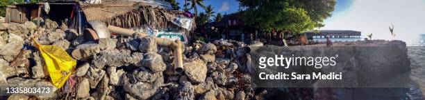 Homes stand above a wall made from coral in the village of Eita located on South Tarawa in the central Pacific island nation of Kiribati on May 25,...