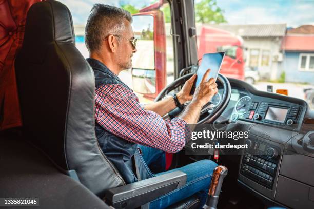 reifer lkw-fahrer mit mobiler app - lkw kabine stock-fotos und bilder