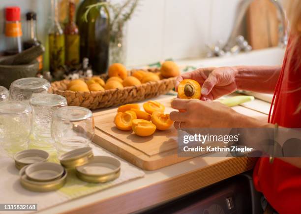 woman preparing to make apricot jam, jars and fruit on kitchen counter - à maturité photos et images de collection