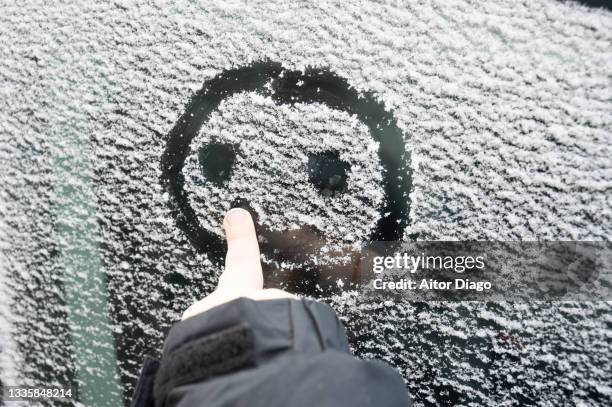 finger of a child (unrecognizable) painting a face on the glass of a frozen car. - snöyra bildbanksfoton och bilder