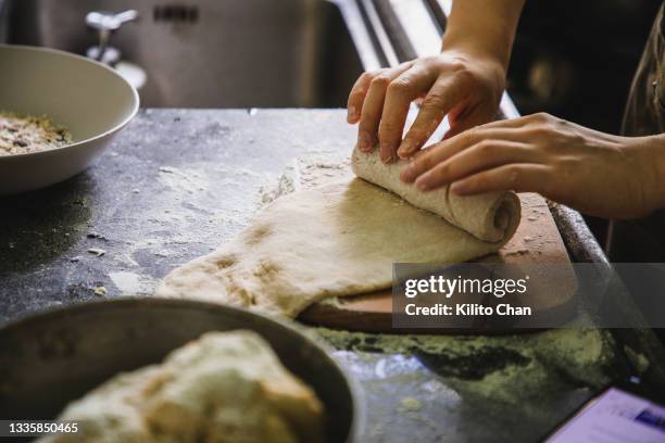 woman making bread rolls on a wooden board on kitchen counter - weizenvollkorn stock-fotos und bilder