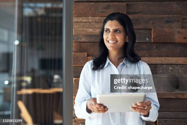 shot of a mature businesswoman using a digital tablet in an office - 50 year old indian lady stock pictures, royalty-free photos & images