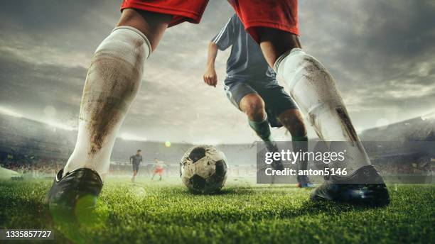 close up legs of football or soccer players during football match at a stadium filled with spectators, fans. show, sport, motion, action, activity concept - kicking stock pictures, royalty-free photos & images