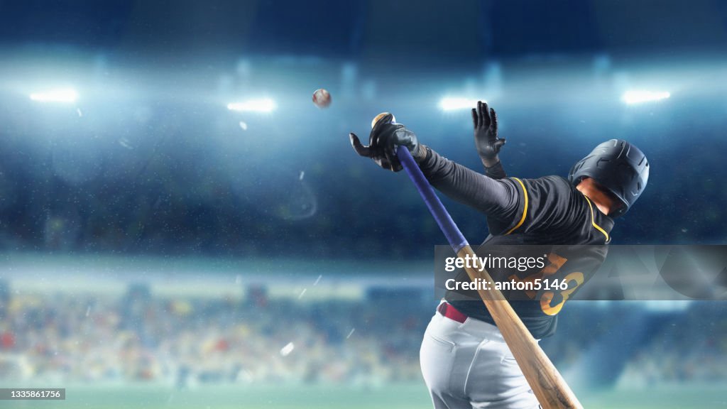 Jugador de béisbol profesional en movimiento, acción durante el partido en el estadio sobre el cielo azul de la tarde con focos. Concepto de deporte, espectáculo, competición.