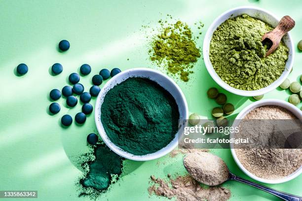 spirulina, maca and moringa powders on green background - maca plant stock pictures, royalty-free photos & images