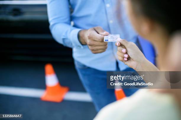 driving student receiving her licence - rijbewijs stockfoto's en -beelden