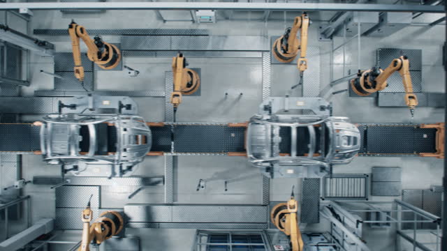 Aerial Car Factory 3D Concept: Automated Robot Arm Assembly Line Manufacturing High-Tech Green Energy Electric Vehicles. Construction, Welding Industrial Production Conveyor. Top View Time-Lapse Loop