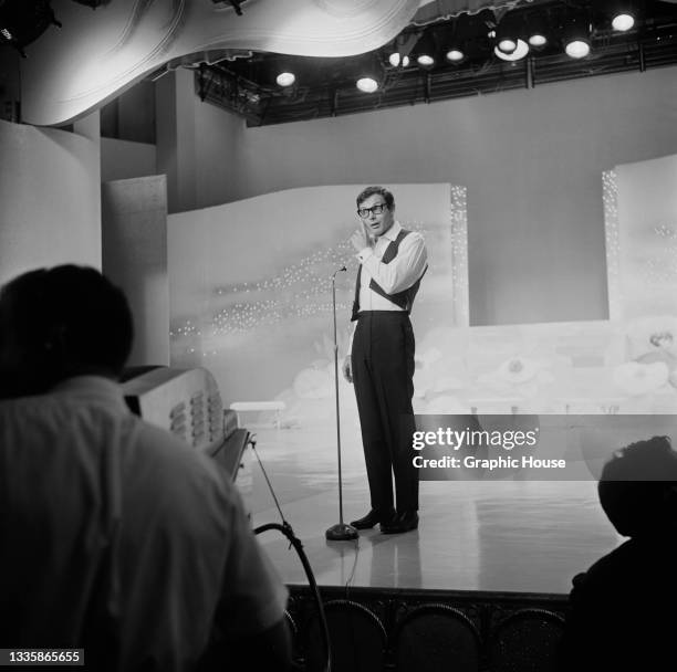 American actor Adam West , wearing a white shirt with a black waistcoat and black trousers, hosts the first Miss Teen International beauty contest in...