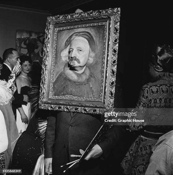 Guest wearing a costume comprising a framed portrait through which they put their face at the Artists' Equity Masquerade Ball, held at the Hotel...