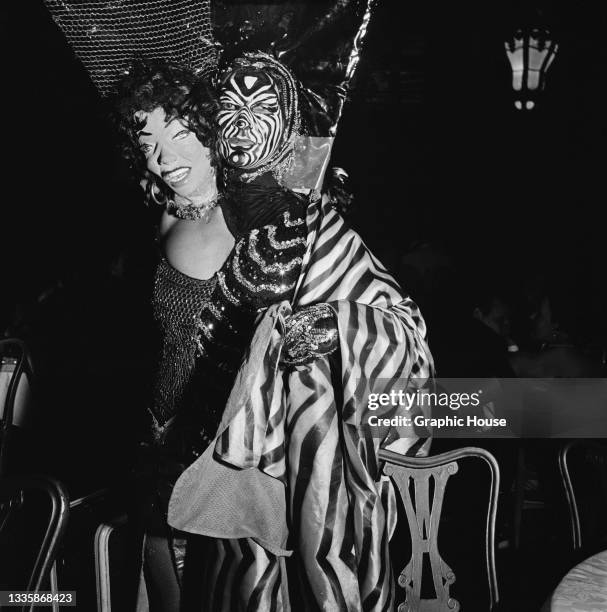 Guest wearing a striped costume with a matching striped face mask and a false second head on their right shoulder, at the Artists' Equity Masquerade...