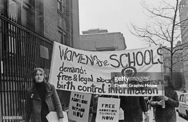 Protestors carry a banner reading 'Women in the schools demand free and legal abortion on demand, birth control information' featuring a raised fist...