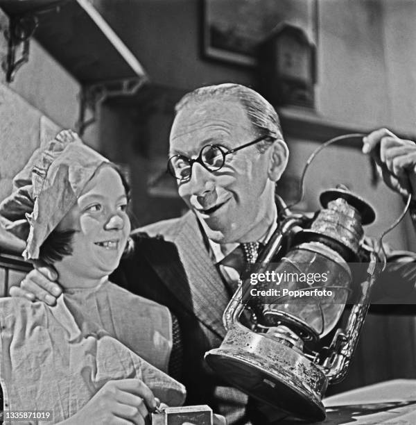 English comedian and actor Arthur Askey and child actress Vera Frances on set during filming of the Gainsborough Pictures comedy film 'Back-Room Boy'...