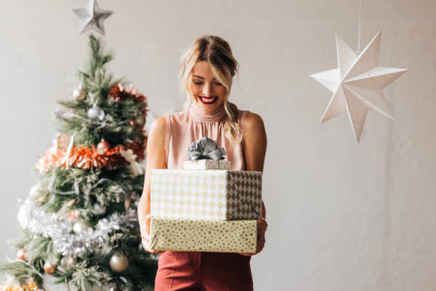 mujer feliz sosteniendo un regalo de navidad en sus manos - mujer navidad fotografías e imágenes de stock