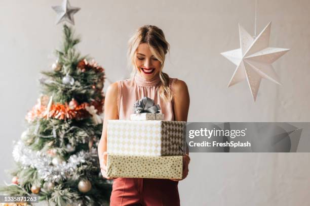 happy woman holding a christmas presents in her hands - kerstkado stockfoto's en -beelden