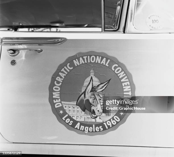 Close-up of a Chevrolet Impala car, featuring a 'Democratic National Convention Los Angeles, 1960' badge on the driver's door, parked in the lot of...