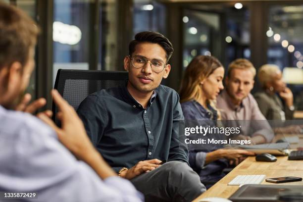 colleagues discussing at desk in creative office - boss and employee stockfoto's en -beelden