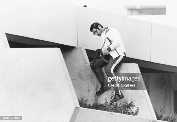 An armed police officer wearing a tracksuit and holding a Walther machine pistol drops to a lower level to maintain surveillance after Palestinian...