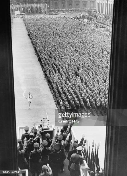 German athlete Fritz Schilgen , runs past storm troopers and Hitler Youth, with the Olympic torch on his way to lighting the Olympic flame at the...