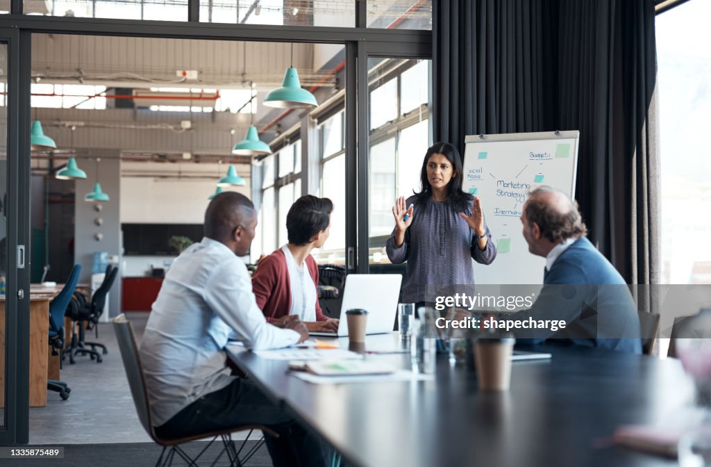 Shot of a mature businesswoman using a whiteboard during a meeting with her colleagues in an office