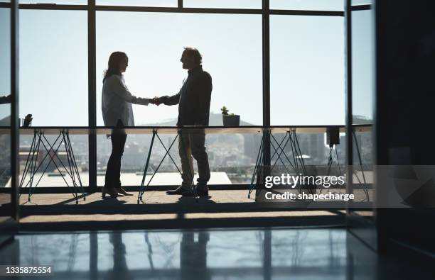 shot of two businesspeople shaking hands in an office - handshake silhouette stock pictures, royalty-free photos & images