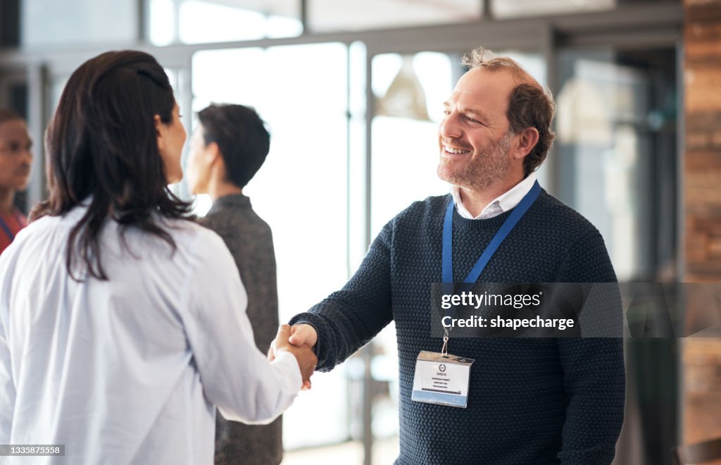 Aufnahme eines reifen Geschäftsmannes, der einem Teilnehmer einer Konferenz die Hand schüttelt
