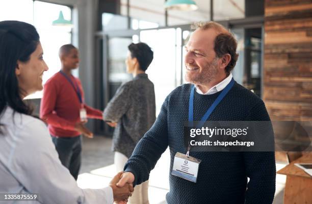 shot of a mature businessman shaking hands with an attendee at a conference - trade show stock pictures, royalty-free photos & images