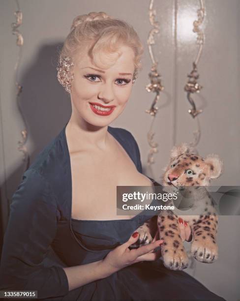 British glamour model and actress Sabrina , wearing a low-cut blue dress with a matching blue shrug, poses with a toy leopard at her home in London,...