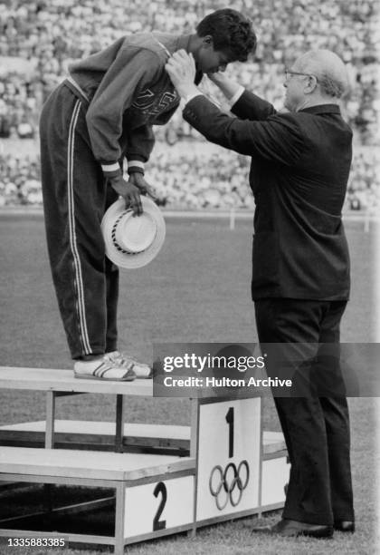 American sprinter Wilma Rudolph is presented with her gold medal by American President of the International Olympic Committee Avery Brundage after...