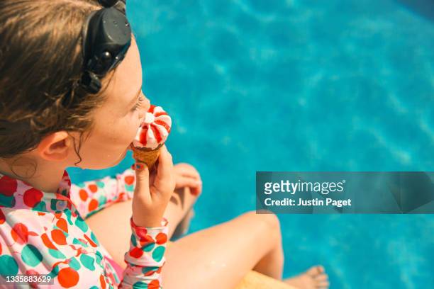 young girl eating an ice cream by the swimming pool - bath relaxation stock pictures, royalty-free photos & images