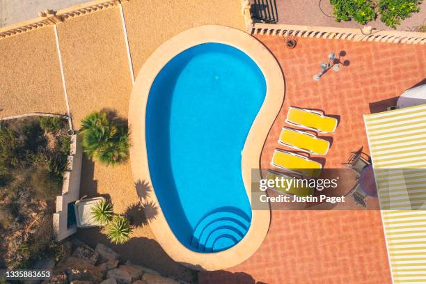 drone view looking down onto swimming pool and terrace of holiday villa in spain - man in swimming pool stock-fotos und bilder