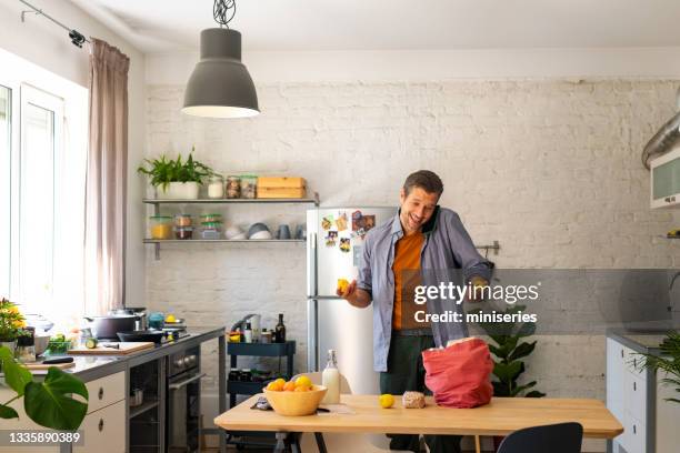 cooking at home: handsome man with mobile preparing to cook - canvas bag stock pictures, royalty-free photos & images