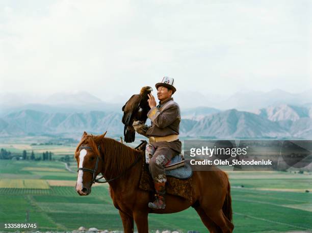 eagle hunter on horse in steppe in kyrgyzstan - kyrgyzstan people stock pictures, royalty-free photos & images