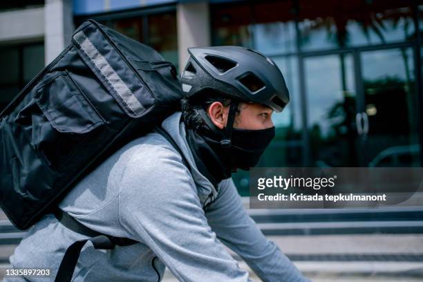 young asian man delivery man riding bicycle in the city . - bicycle messenger stock pictures, royalty-free photos & images