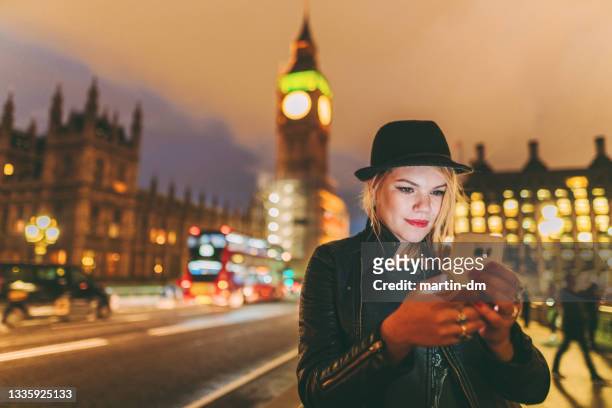 frau in london bei nacht, die auf ein taxi wartet - london taxi stock-fotos und bilder