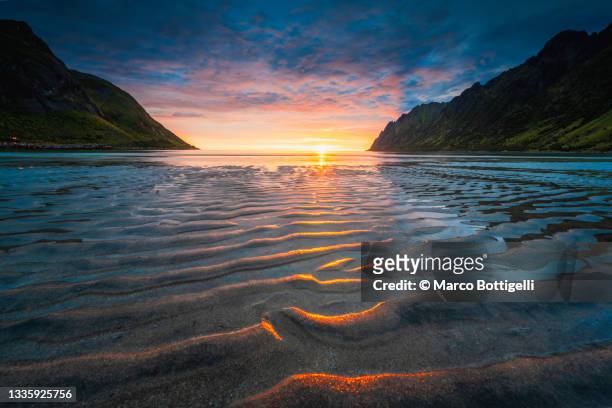 ripples of the sand at unset during midnight sun in a fjord, norway - midnight sun norway stockfoto's en -beelden