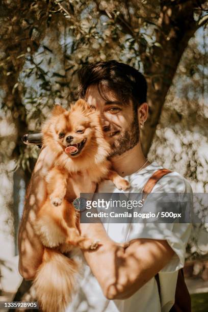 man with pomeranian standing against trees,italy - spitz type dog stock pictures, royalty-free photos & images