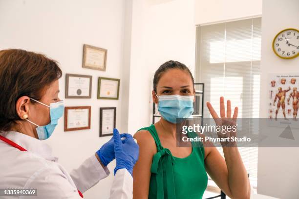 mature woman getting her fourth dose of a covid-19 vaccination - dose 個照片及圖片檔