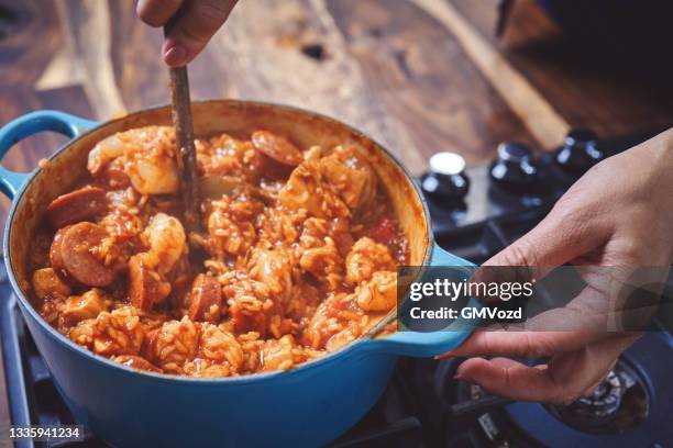 preparing cajun style chicken, shrimp and sausage jambalaya in a cast iron pot - jambalaya imagens e fotografias de stock