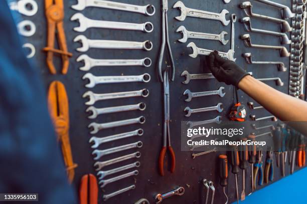 mujer negra tomando llaves de la pared negra con diferentes herramientas - herramienta-de-mano fotografías e imágenes de stock