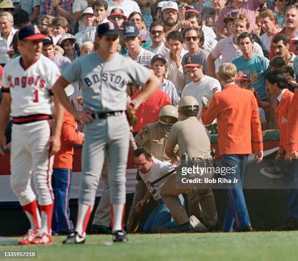 Police escort then arrest a fan who ran onto the field during Game 5 of ALCS, October 12, 1986 in Anaheim, California.